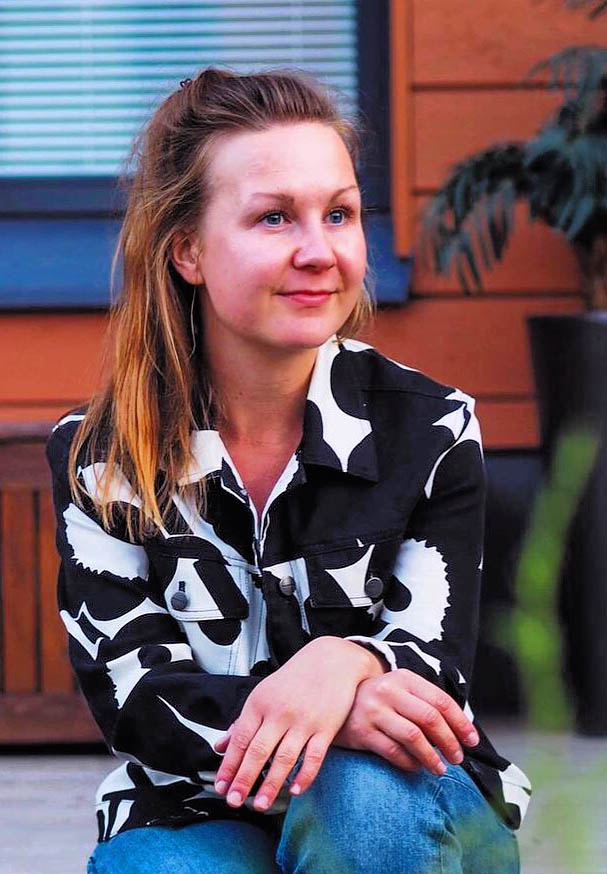 Marleena Antikainen istuu ulkona kuistilla ja hymyilee. Hän katsoo kamerasta ohi.