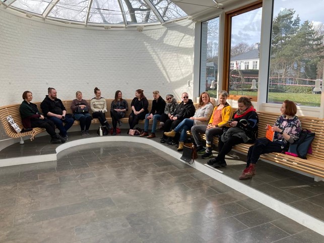 Ihmisiä istumassa penkillä puoliringissä.