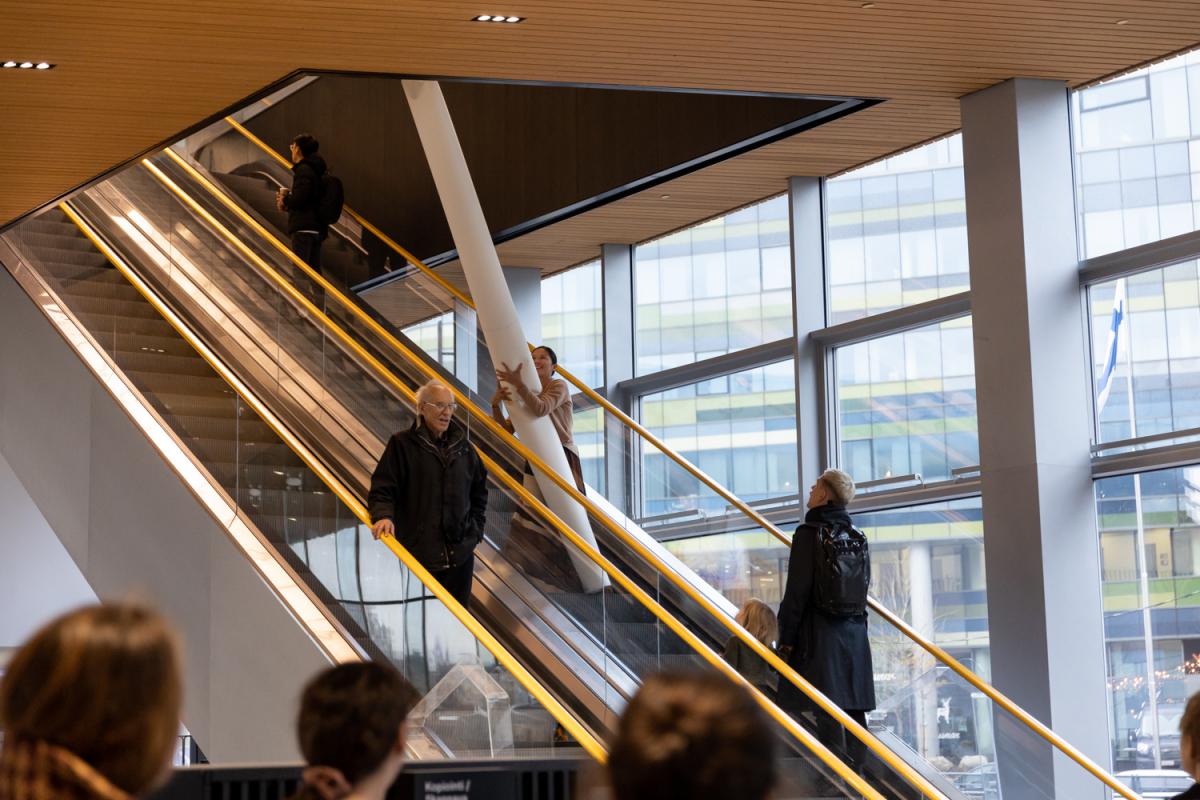 Performer holding the paper pillar in escalator